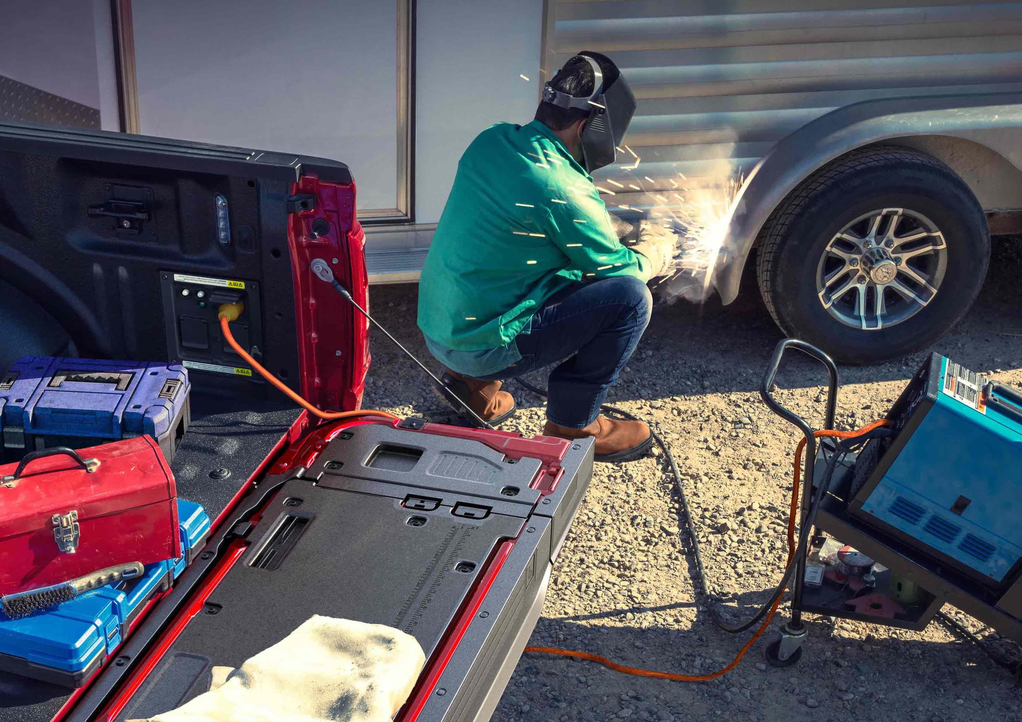 Person using a TIG welder that's plugged into the Pro Power Onboard feature located in the truck bed